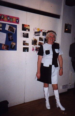 Joan poses in front of a display of old photos of Pat
